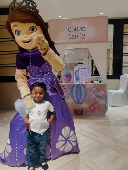 Making magical memories with a princess. A young guest and a party mascot pose in front of our themed cotton candy stall.