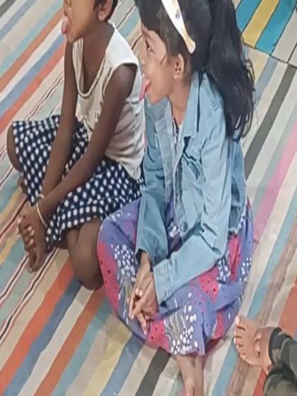 Two children playfully stick out their tongues, mimicking the chameleon in the story. This is a perfect example of learning through imitation and fun.