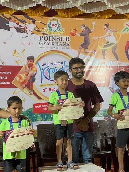 A coach proudly stands with the winners on the podium. The success of our students is a shared victory that reflects the dedication of the entire IMFC family, including coaches and parents.