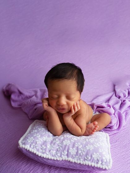 Another variation of the safe 'froggy pose', this time with the baby resting their head on a small pillow. This pose requires specialized training to execute safely.