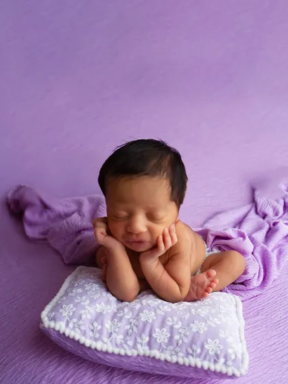 Another variation of the safe 'froggy pose', this time with the baby resting their head on a small pillow. This pose requires specialized training to execute safely.