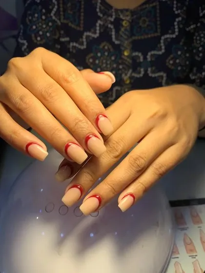 A minimalist and modern design featuring a nude base with a simple, curved red line. This look gives the impression of a French manicure with an artistic, abstract twist.