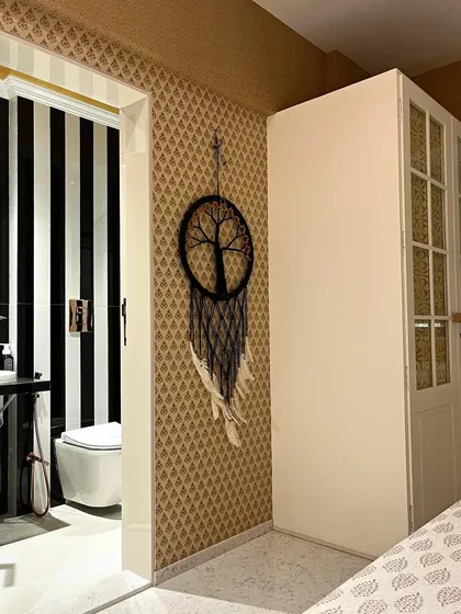 Another angle of the Bohemian bedroom, showing the contrast between the patterned wallpaper and the bold black-and-white stripes of the bathroom, creating a dynamic yet cohesive design.