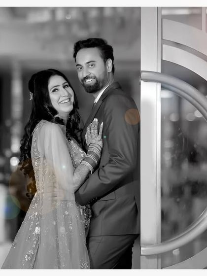 An artistic take on a couple portrait, using a color splash effect. The couple is highlighted in soft color against a black and white background, making them the clear focus of the image.