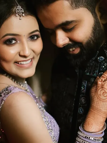 The bride looks directly at the camera with a confident smile, her hand resting on her groom's shoulder. This shot beautifully captures her personality and the couple's easy connection.