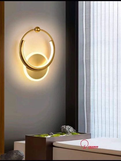 A modern wall sconce with interlocking rings in a gold finish. This elegant fixture is perfect for a contemporary living room or hallway.
