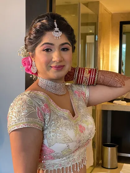 A side view of the bride's floral updo, showing how the pink roses complement her pastel lehenga.