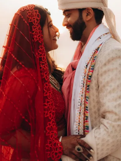 A close-up, romantic shot of Anushka and Himanshu. The bride's red veil adds a beautiful pop of color and a traditional touch to this intimate portrait.