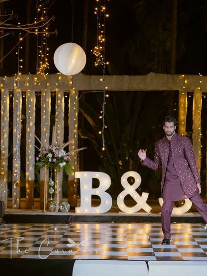 A candid moment of the groom enjoying his performance on the stylish checkered dance floor, surrounded by the warm glow of the stage lights.