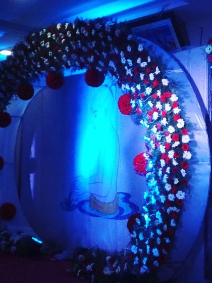 This custom backdrop features a floral arch in red and white, framing a personalized graphic. The blue uplighting creates a cool, modern contrast for a unique evening event.
