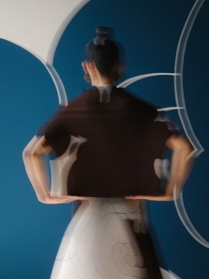A motion-blur shot that abstracts the form of the model and the cloud-print dress, turning the image into a piece of kinetic art.