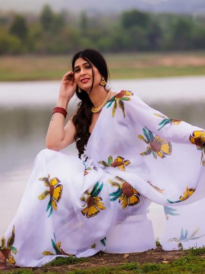 A relaxed and happy seated portrait by the lake. The flowing saree and her bright smile create a picture of pure contentment.