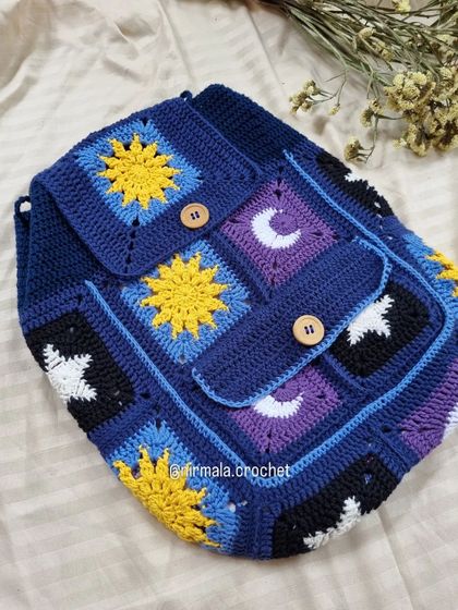 A detailed look at the galaxy backpack, showcasing the different celestial granny square designs and sturdy wooden button closures.