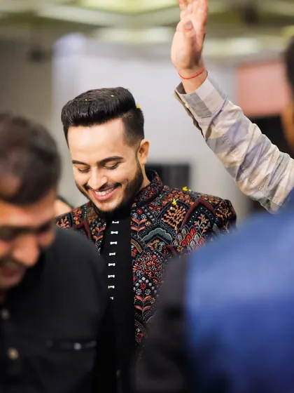 A moment of joy and celebration. The groom's vibrant outfit and happy smile are the highlights of the evening.
