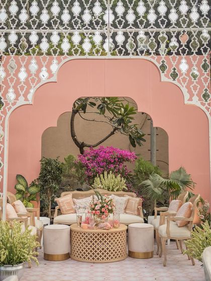 A beautiful photo spot at the 'Gulab Bagh' wedding, where intricate white jali work frames a lounge area set against a soft pink wall.