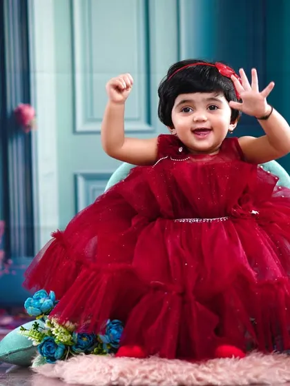 She's one! This little girl waves excitedly, celebrating her first birthday in a gorgeous red gown.