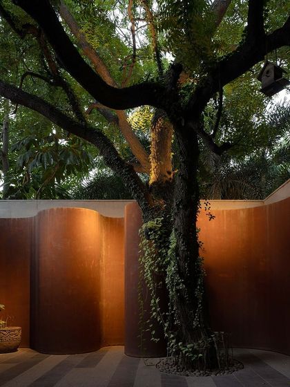 A curving Corten steel wall enveloping a mature tree at KEUS. The uplighting at night accentuates the texture of the steel and the form of the tree, creating a powerful sculptural statement.