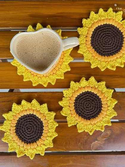 A cozy lifestyle shot of our handmade crochet sunflower coasters. These are perfect for adding a pop of color to your home decor or including in a gift hamper. We offer them in multiple sizes to fit any mug.