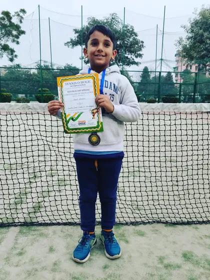 Manit Shokeen proudly displaying his bronze medals for both the U-10 and U-8 categories. His dedication on the court led to this fantastic achievement in the Tennisoholic tournament.
