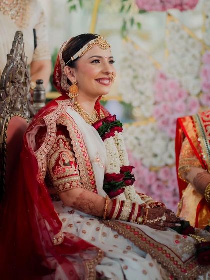 A candid moment from the wedding ceremony. The bride's makeup remains flawless and radiant, highlighting her joyful expression as she sits at the mandap.
