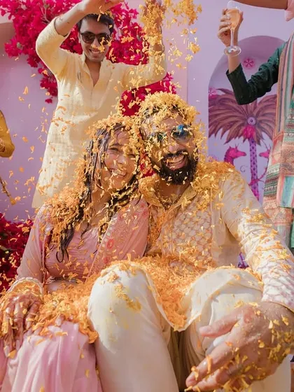 A Haldi ceremony bursting with life and color. This moment of pure, uninhibited fun, with the couple showered in marigold petals by their loved ones, is what makes Indian weddings so special.