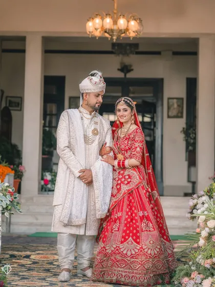 A timeless full-length portrait of the bride and groom in their wedding attire, standing before the entrance of the heritage venue.