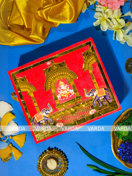 This vibrant red invitation box is adorned with golden illustrations of Lord Ganesha seated in a temple arch, flanked by elephants. It’s a perfect choice for a traditional wedding ceremony, invoking blessings and grandeur.