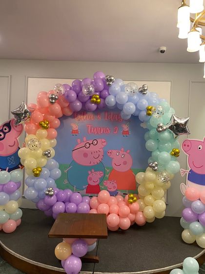 A Peppa Pig themed circular balloon arch with silver star accents.