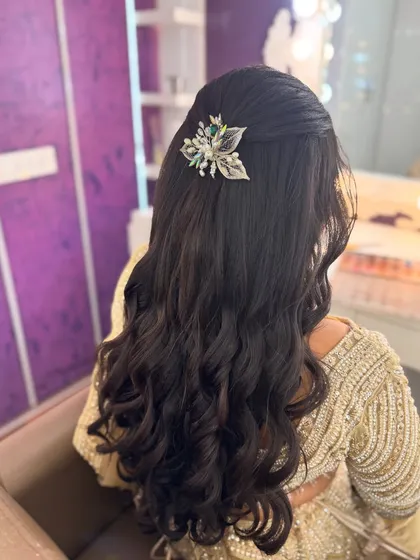 A view of the modern, wavy hairstyle I created for Prithivi's reception. The half-up style is adorned with a beautiful silver and green accessory.