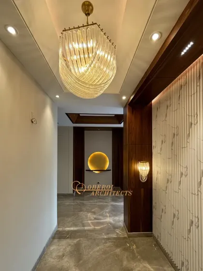 A hallway that is anything but ordinary, with a sculptural chandelier, fluted wall panels, and a backlit art niche that draws the eye forward.