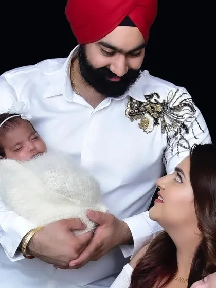 A heartwarming family portrait with both parents lovingly looking at their newborn daughter. These first family photos are a priceless memory of your new beginning.