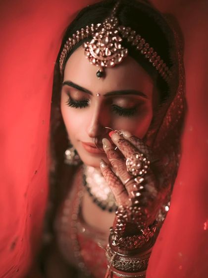 An artistic close-up of Vaishali, her face partially covered by her red veil, creating a moody and romantic image.