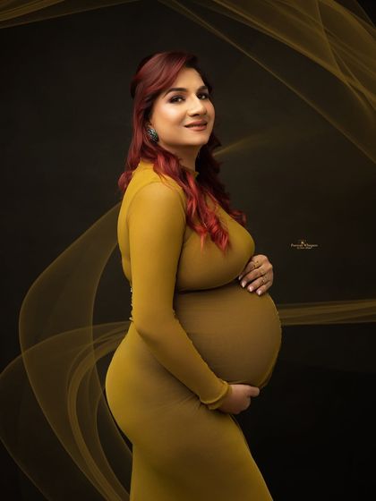 A simple and beautiful solo portrait against a dark backdrop. The form-fitting olive gown and soft lighting perfectly accentuate the baby bump.