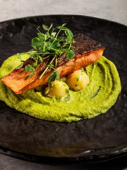 A golden-seared salmon fillet rests on a bed of vibrant truffle pea purée. This dish is an experience in itself, balancing a buttery finish with earthy, aromatic flavours.