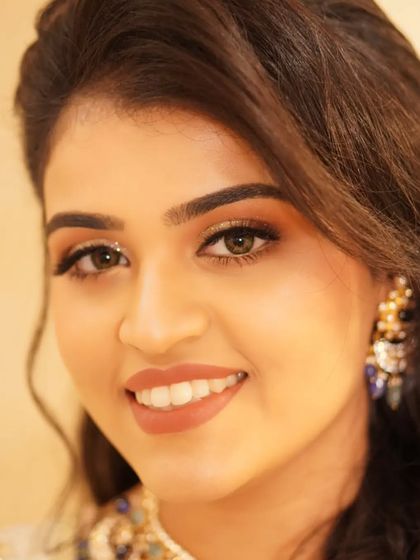 A bright, forward-facing portrait of Payal. Her reception makeup is flawless, with sparkling eyes and a warm, inviting smile that lights up the frame.