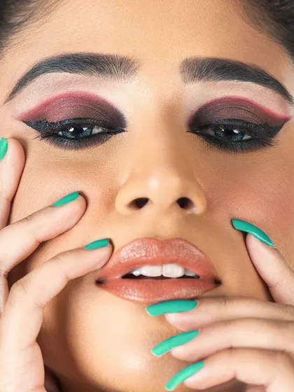 A detailed close-up of a high-fashion eye. This look features a dark, blended smokey eye framed by a sharp, contrasting red graphic liner, demonstrating precision and a bold artistic approach.