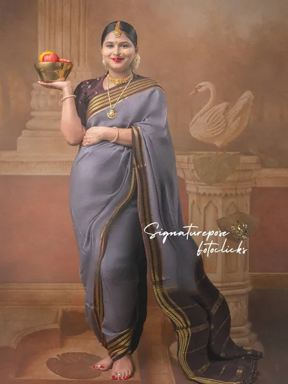 A standing portrait showcasing the full traditional look, from the saree to the props and backdrop.