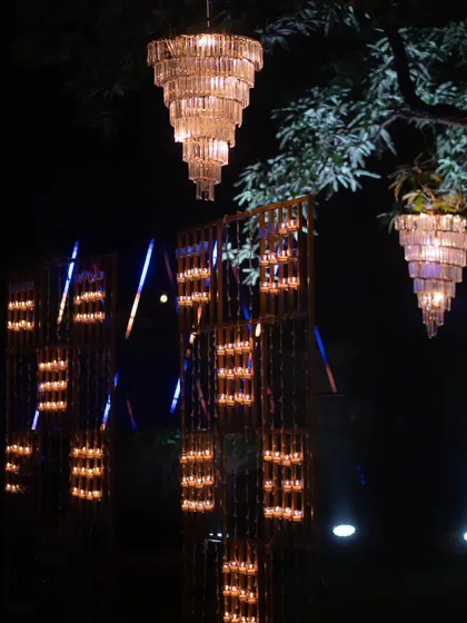 An artful installation of candles and hanging chandeliers for a Diwali event. The warm, flickering light creates an intimate and traditionally festive atmosphere with a modern twist.
