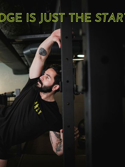 A trainer demonstrates a deep stretch using a power rack. We emphasize that knowledge of movement and mobility is just the start of a true fitness journey.
