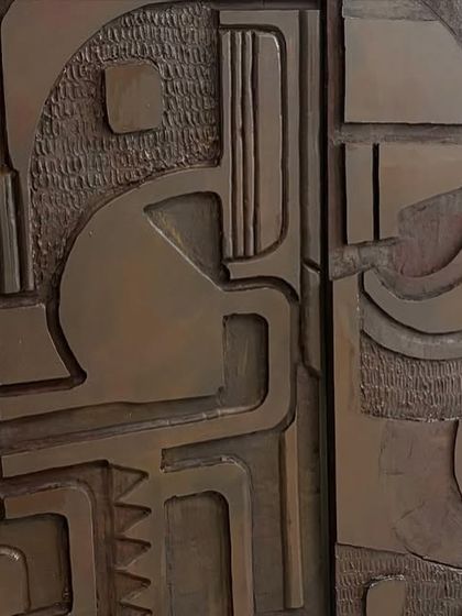 A close-up where two of the wooden panels meet, showing the continuous flow of the abstract design across the separate pieces.