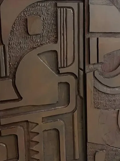A close-up where two of the wooden panels meet, showing the continuous flow of the abstract design across the separate pieces.