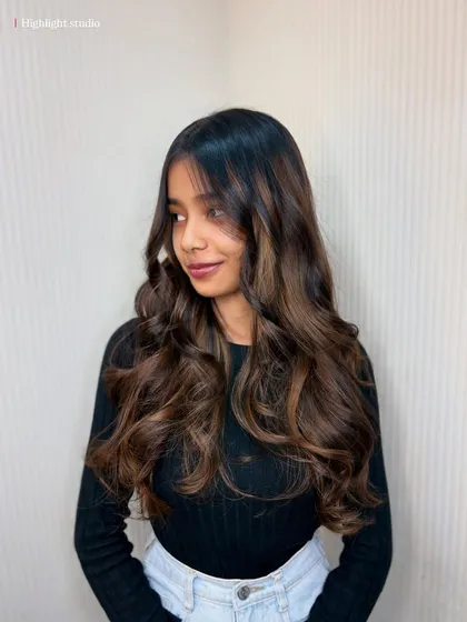This client is glowing with her new balayage. The soft curls and face-framing pieces create a stunning look.