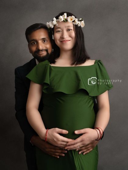 A happy and bright studio portrait of a couple. The floral crown on the mom-to-be adds a lovely, natural touch to the photo.