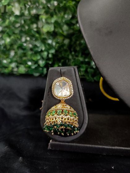 A simple and elegant jhumka with a single kundan stone and a bell of green beads.