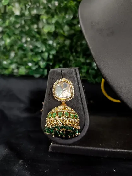A simple and elegant jhumka with a single kundan stone and a bell of green beads.
