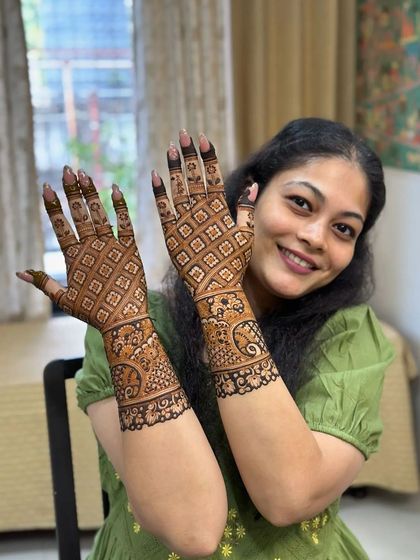 A smiling client showing off her intricate jaal-patterned mehndi.