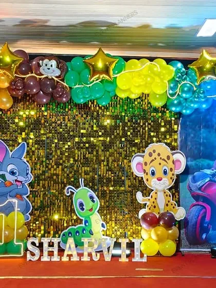 A fun jungle-themed birthday stage with a shimmering gold backdrop.