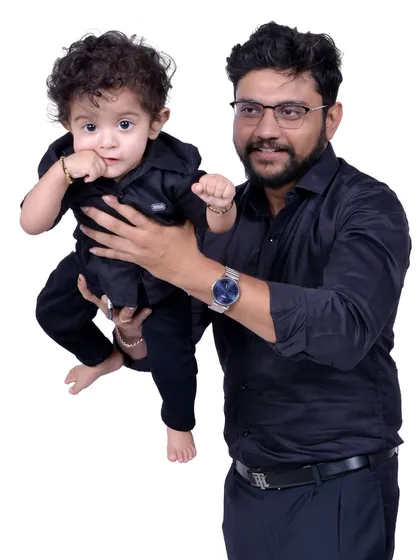 A father and son portrait with matching black shirts against a clean white background. These simple, coordinated shoots are a great way to capture the bond between a parent and child.