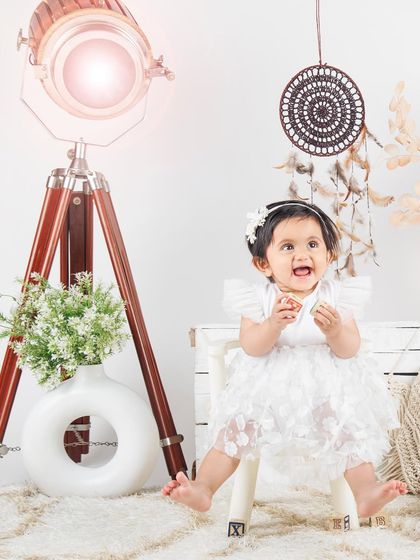 A joyful moment in our lifestyle set, with this little girl in a white dress looking up with a happy expression.