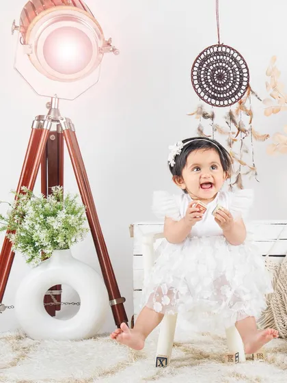 A joyful moment in our lifestyle set, with this little girl in a white dress looking up with a happy expression.